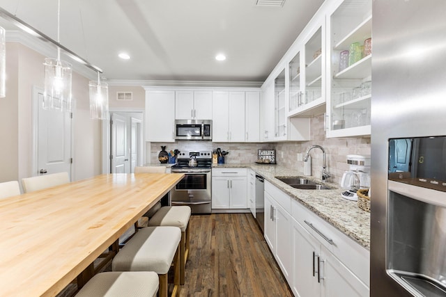 kitchen with appliances with stainless steel finishes, white cabinetry, dark hardwood / wood-style floors, pendant lighting, and sink