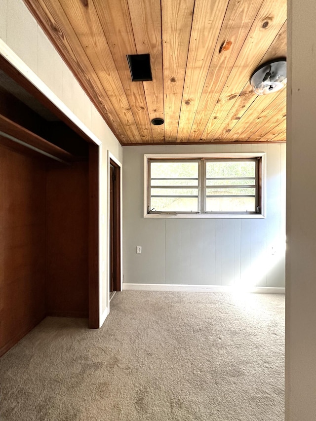 unfurnished bedroom with carpet, a closet, wood ceiling, and vaulted ceiling