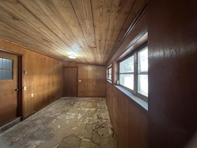 corridor with wooden walls, wood ceiling, and lofted ceiling