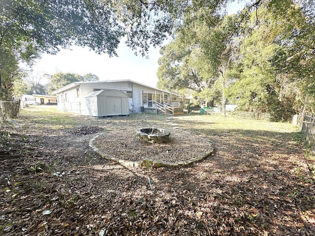 view of yard with a shed and an outdoor fire pit