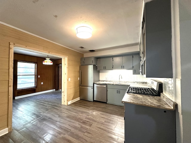 kitchen with dark hardwood / wood-style floors, wood walls, appliances with stainless steel finishes, and tasteful backsplash