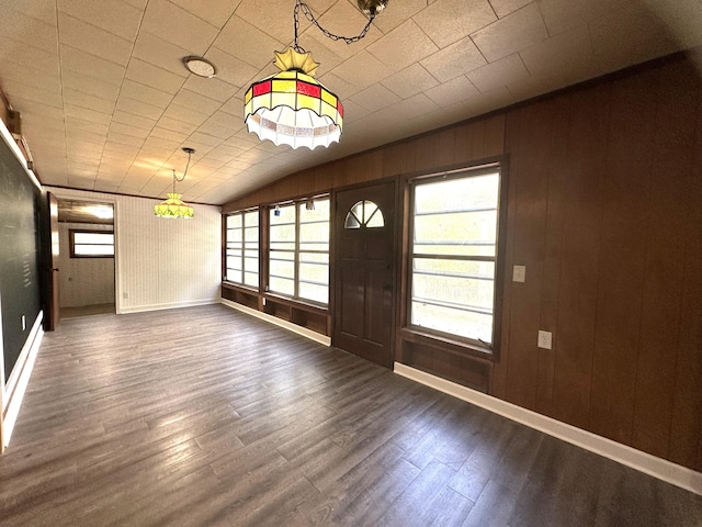 foyer entrance with dark hardwood / wood-style flooring, lofted ceiling, and wooden walls