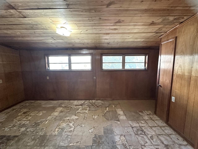 basement featuring wood ceiling, a healthy amount of sunlight, and wood walls