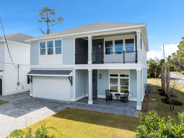 view of front of home featuring a front yard, central AC unit, a garage, and a balcony