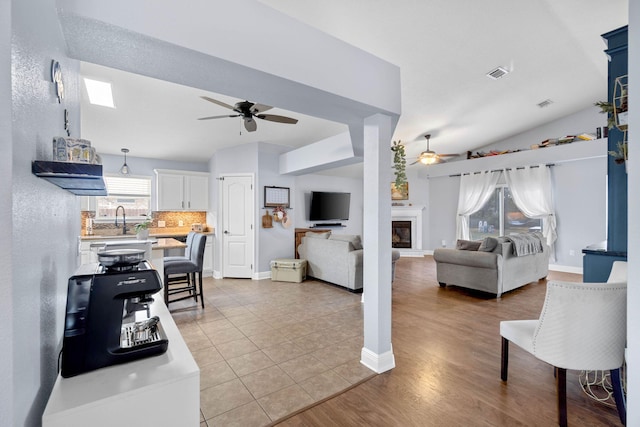 living room featuring light hardwood / wood-style floors, vaulted ceiling, and ceiling fan