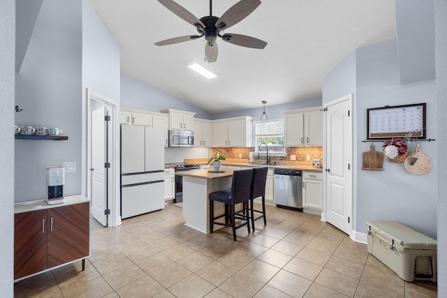 kitchen with a breakfast bar area, appliances with stainless steel finishes, a kitchen island, sink, and decorative light fixtures