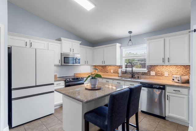 kitchen with sink, a center island, vaulted ceiling, white cabinetry, and appliances with stainless steel finishes