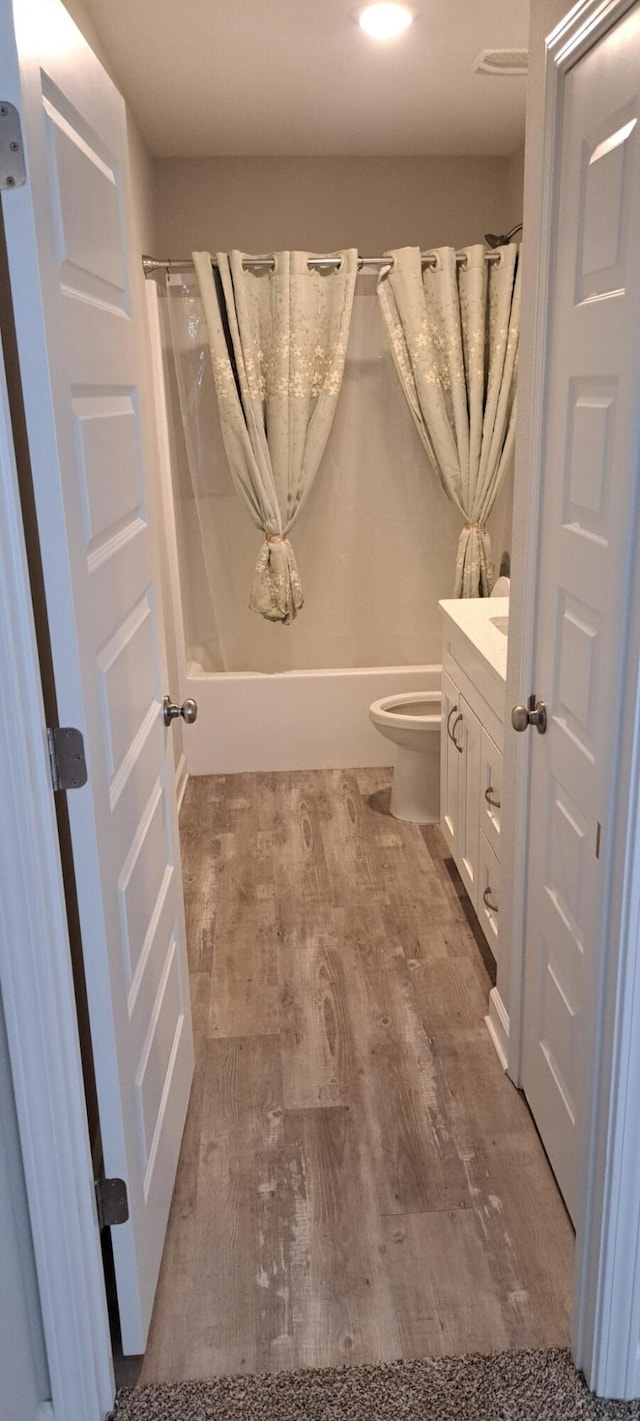 full bathroom featuring toilet, hardwood / wood-style floors, vanity, and shower / tub combo with curtain