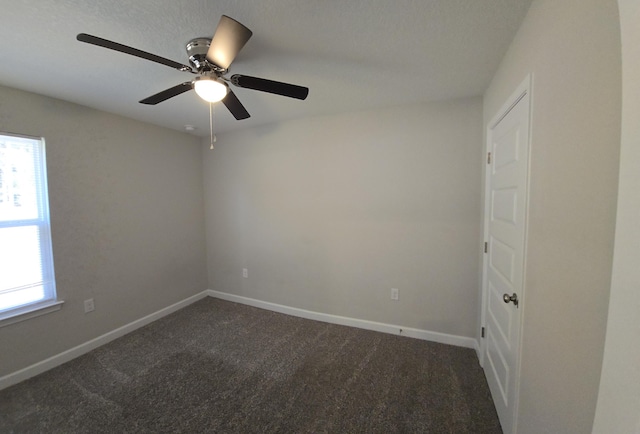 empty room with ceiling fan and dark colored carpet