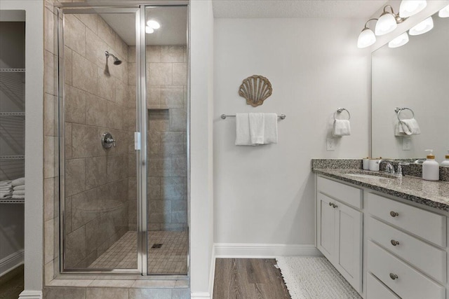 bathroom featuring hardwood / wood-style flooring, a shower with door, and vanity