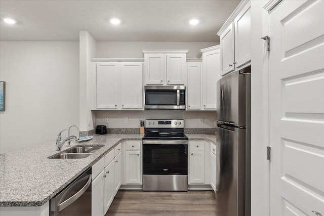 kitchen featuring light stone counters, stainless steel appliances, white cabinetry, dark hardwood / wood-style floors, and sink