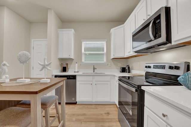 kitchen featuring stainless steel appliances, white cabinets, sink, and light wood-type flooring