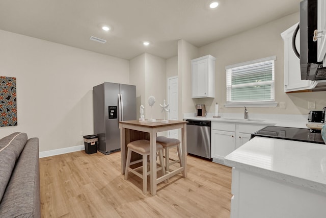 kitchen with light hardwood / wood-style flooring, appliances with stainless steel finishes, and white cabinets