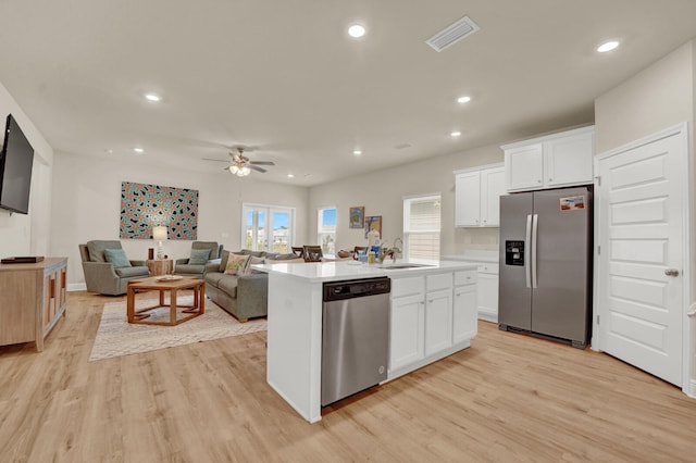 kitchen featuring white cabinetry, light wood-type flooring, appliances with stainless steel finishes, and a kitchen island with sink