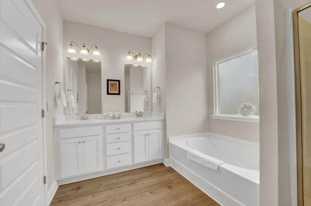 bathroom with hardwood / wood-style floors, a bath, and vanity