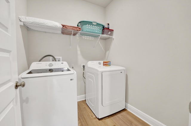 laundry area featuring washer and dryer and light hardwood / wood-style flooring