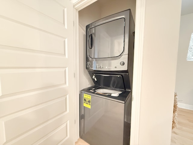 laundry room featuring light hardwood / wood-style floors and stacked washer / drying machine