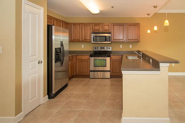 kitchen with kitchen peninsula, appliances with stainless steel finishes, a breakfast bar, pendant lighting, and sink