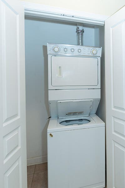 laundry area featuring stacked washer and dryer and tile patterned flooring