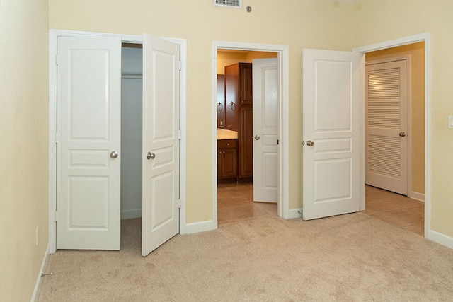 unfurnished bedroom featuring light colored carpet and ensuite bath