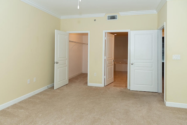 unfurnished bedroom with crown molding, light carpet, and a walk in closet