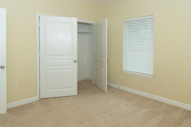 unfurnished bedroom with a closet and light colored carpet