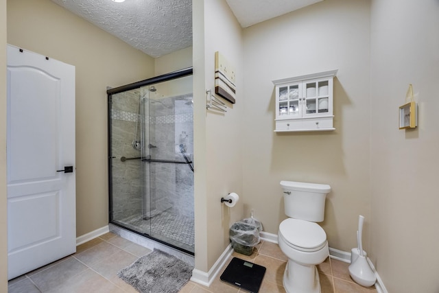 bathroom featuring tile patterned floors, a textured ceiling, toilet, and an enclosed shower