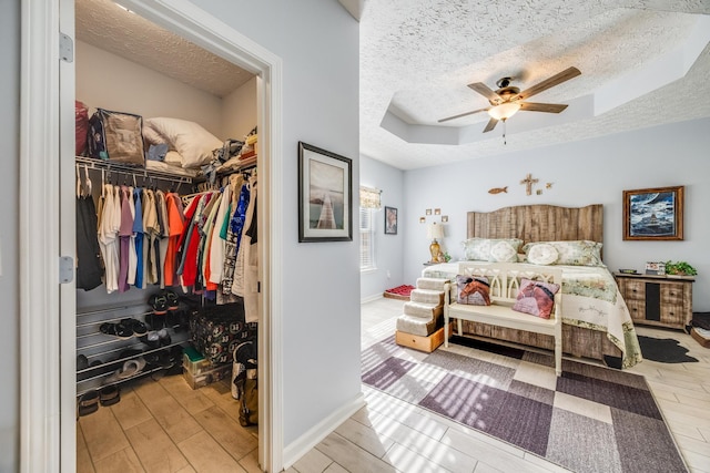 bedroom featuring light hardwood / wood-style floors, a closet, a tray ceiling, and ceiling fan