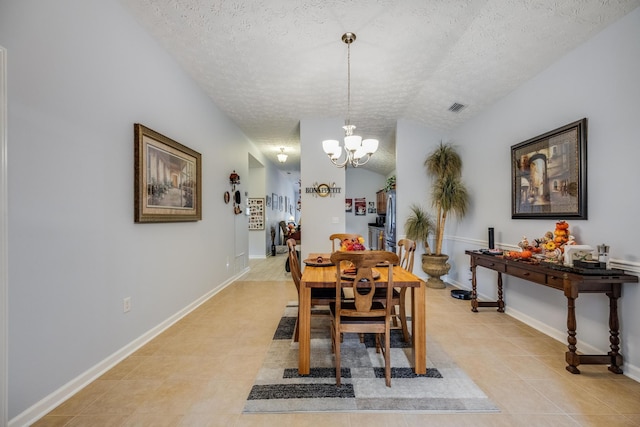 dining space featuring a notable chandelier, a textured ceiling, and light tile patterned flooring