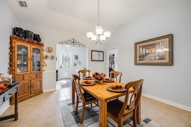 dining room featuring an inviting chandelier, a textured ceiling, and light tile patterned flooring