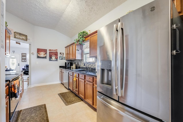 kitchen featuring tasteful backsplash, appliances with stainless steel finishes, sink, a textured ceiling, and vaulted ceiling