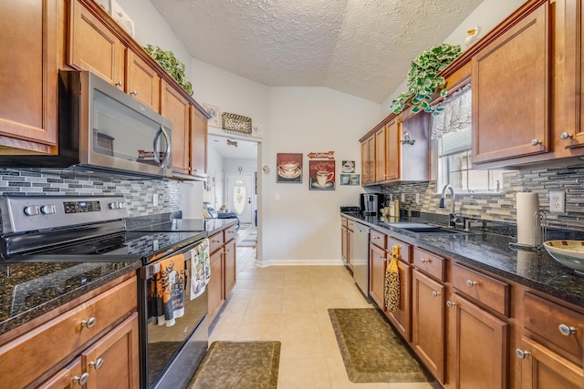 kitchen with backsplash, sink, vaulted ceiling, appliances with stainless steel finishes, and a textured ceiling