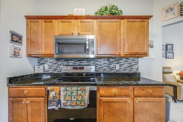 kitchen featuring appliances with stainless steel finishes, tasteful backsplash, and dark stone counters