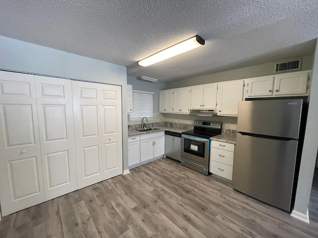 kitchen with stainless steel appliances, sink, light wood-type flooring, and white cabinets