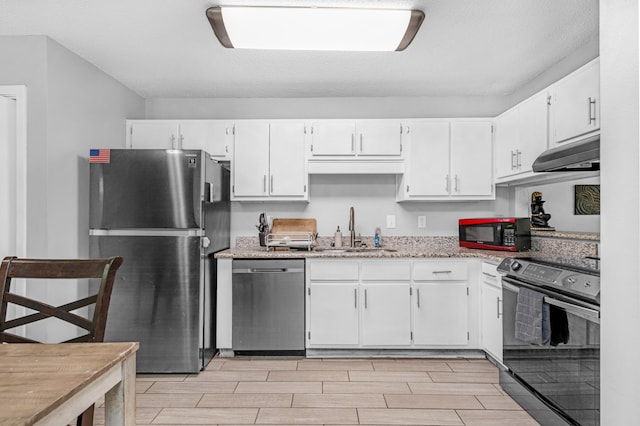 kitchen with sink, light stone counters, white cabinets, and appliances with stainless steel finishes