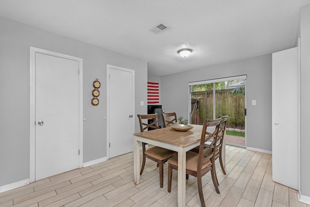 dining area featuring light hardwood / wood-style flooring and a textured ceiling