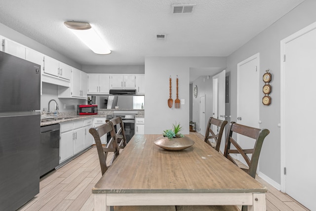 kitchen with sink, stainless steel appliances, white cabinetry, and a textured ceiling