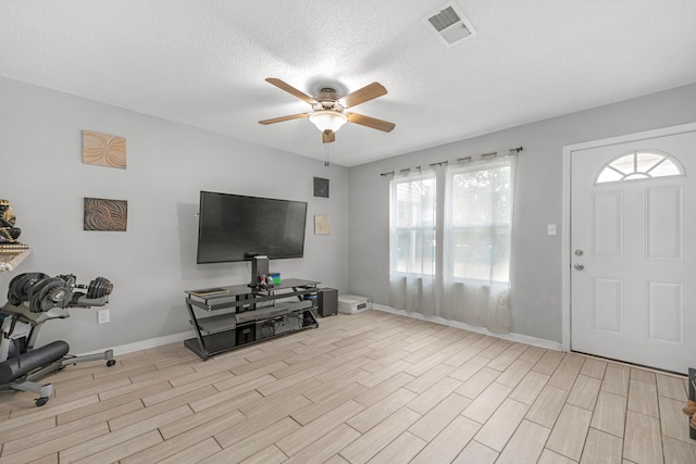 interior space featuring ceiling fan, light hardwood / wood-style floors, and a textured ceiling