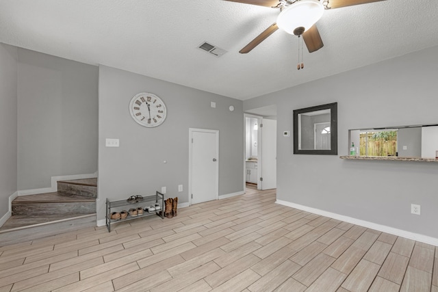 unfurnished living room featuring ceiling fan and a textured ceiling