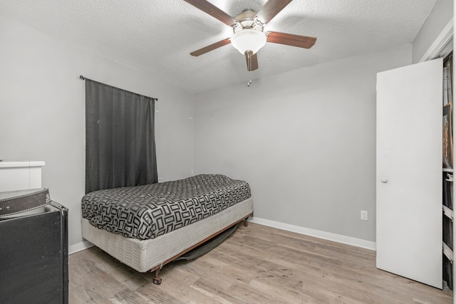 bedroom with ceiling fan, light hardwood / wood-style flooring, and a textured ceiling