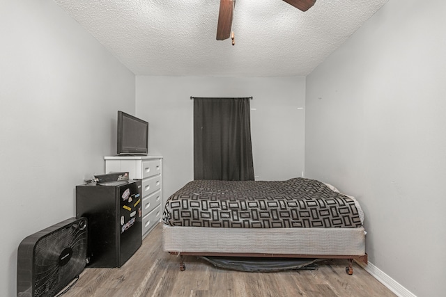 bedroom featuring hardwood / wood-style floors, a textured ceiling, and ceiling fan