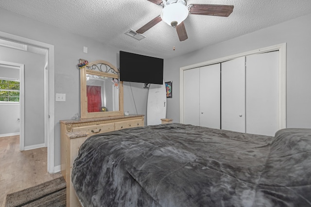 bedroom with a closet, ceiling fan, a textured ceiling, and wood-type flooring