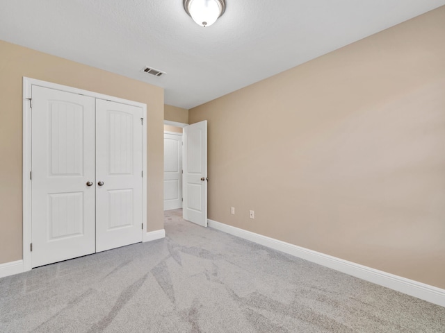 unfurnished bedroom featuring a closet and light colored carpet