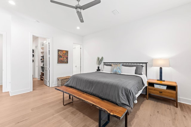 bedroom featuring light hardwood / wood-style flooring, a walk in closet, and ceiling fan