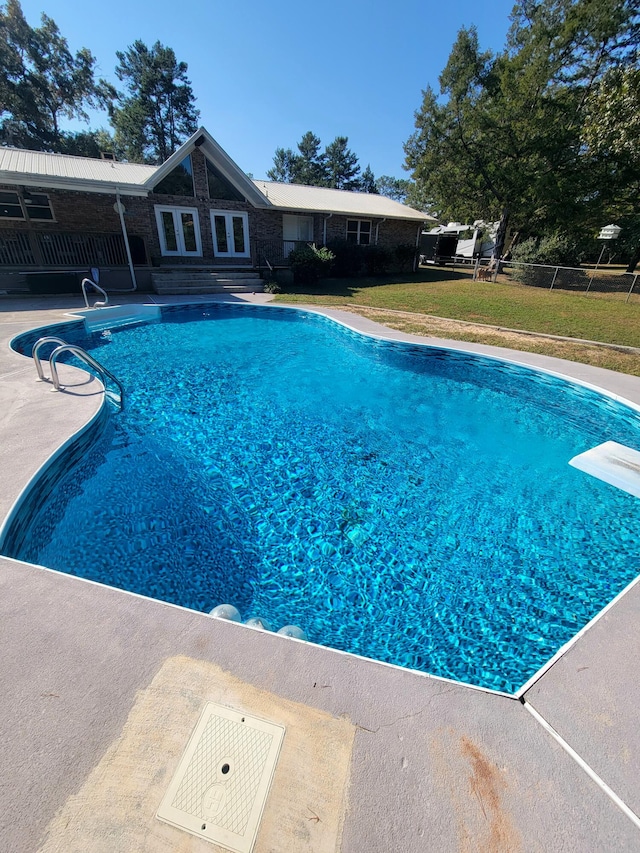 view of swimming pool with a patio, a yard, and a diving board