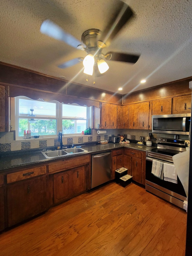 kitchen with stainless steel appliances, a textured ceiling, sink, and hardwood / wood-style floors