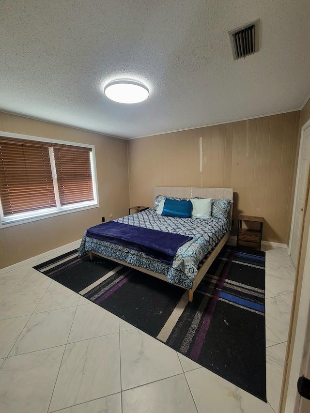 bedroom featuring wood walls and a textured ceiling