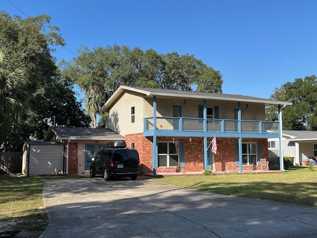 view of front of house featuring a storage shed, a front yard, and a balcony