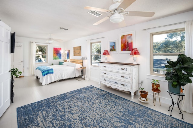 bedroom with a textured ceiling, multiple windows, and ceiling fan