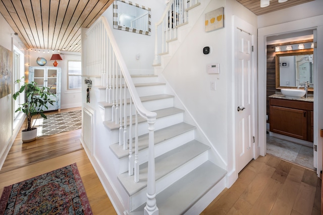 stairway featuring hardwood / wood-style flooring, sink, and wood ceiling